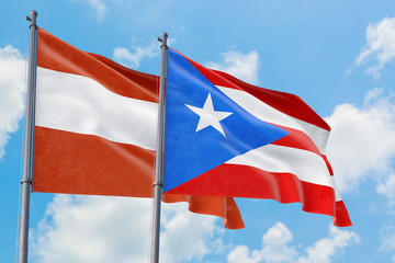 Puerto Rico and Austria flags waving in the wind against white cloudy blue sky together. Diplomacy concept, international relations.