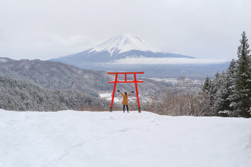 Asian woman tourist travel at Red Japanese Torii pole, Fuji mountain and snow in Kawaguchiko,...