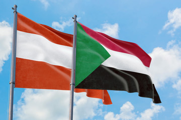 Sudan and Austria flags waving in the wind against white cloudy blue sky together. Diplomacy concept, international relations.