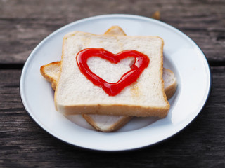 bread with red fruit jam heart shape on white plate