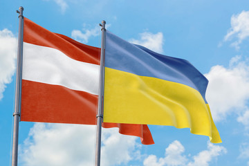 Ukraine and Austria flags waving in the wind against white cloudy blue sky together. Diplomacy concept, international relations.
