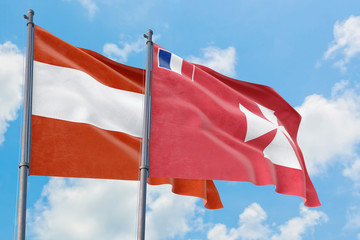 Wallis And Futuna and Austria flags waving in the wind against white cloudy blue sky together....