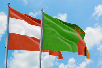 Zambia and Austria flags waving in the wind against white cloudy blue sky together. Diplomacy concept, international relations.