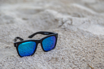 Fototapeta na wymiar Blue sunglasses on white sand
