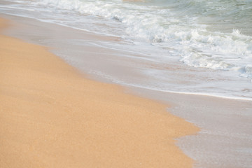 Fototapeta na wymiar Soft foam wave and sea on the sandy beach