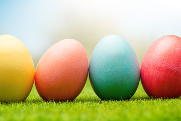 A row of Easter eggs in the fresh green grass in the garden