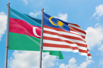 Malaysia and Azerbaijan flags waving in the wind against white cloudy blue sky together. Diplomacy concept, international relations.