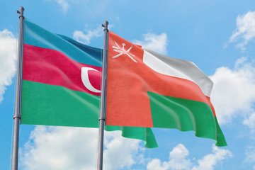 Oman and Azerbaijan flags waving in the wind against white cloudy blue sky together. Diplomacy concept, international relations.