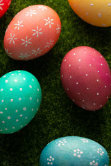 Easter eggs colored on green grass. Congratulations on Easter. Vertical frame.