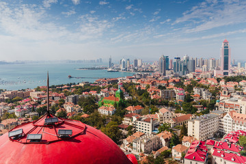 Top view from the hill of Signal Park of red roofs and cityscape of old town and new town seaside of Qingdao, China.Seaside tourist town that is popular with Chinese people. - obrazy, fototapety, plakaty