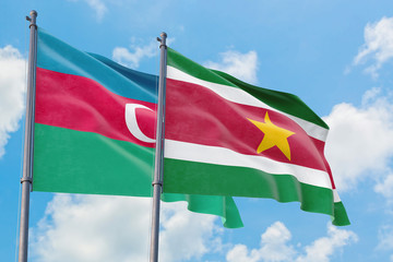 Suriname and Azerbaijan flags waving in the wind against white cloudy blue sky together. Diplomacy concept, international relations.