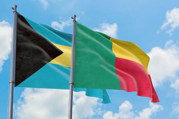 Benin and Bahamas flags waving in the wind against white cloudy blue sky together. Diplomacy concept, international relations.