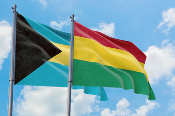 Bolivia and Bahamas flags waving in the wind against white cloudy blue sky together. Diplomacy concept, international relations.