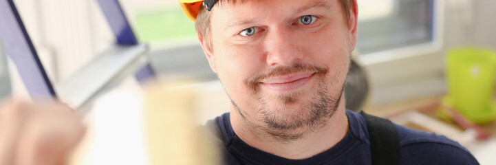Obraz premium Arm of smiling worker hold brush closeup. Manual job workplace DIY inspiration improvement fix shop yellow helmet hard hat joinery startup idea industrial education profession career concept