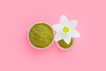 natural henna powder and white flower in a female hand on a pink background. Concept female beauty...