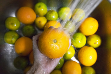 Soaking orange in kitchen sink. Cleaning completely before eating, soaking fruits in water is relatively effective at sanitizing them. 