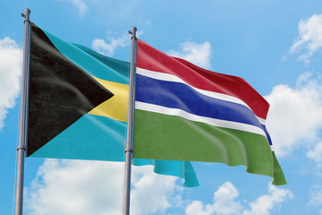 Gambia and Bahamas flags waving in the wind against white cloudy blue sky together. Diplomacy concept, international relations.