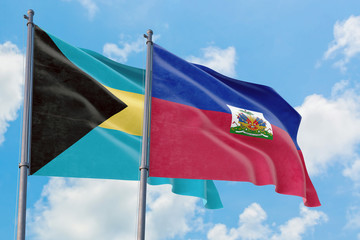 Haiti and Bahamas flags waving in the wind against white cloudy blue sky together. Diplomacy concept, international relations.