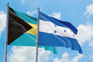 Honduras and Bahamas flags waving in the wind against white cloudy blue sky together. Diplomacy concept, international relations.