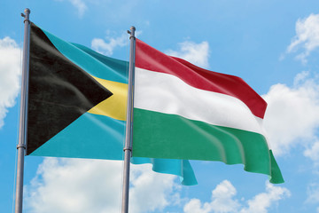 Hungary and Bahamas flags waving in the wind against white cloudy blue sky together. Diplomacy concept, international relations.