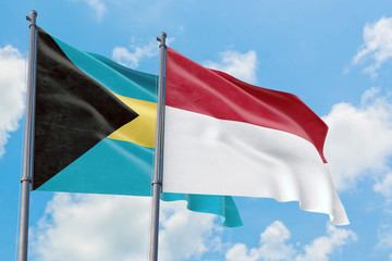 Indonesia and Bahamas flags waving in the wind against white cloudy blue sky together. Diplomacy concept, international relations.