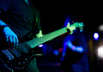 Fototapeta na wymiar A man plays a guitar on a dark stage at a rock concert