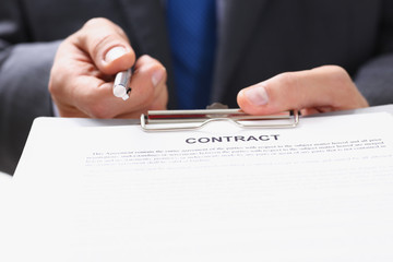 Male arm in suit offer contract form on clipboard pad and silver pen to sign closeup. Strike a bargain for profit, white collar motivation union decision corporate sale insurance agent concept