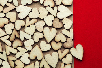Romantic background of dozens of tiny wooden hearts with a single heart on a red card. For love, romance, or Valentine's Day.