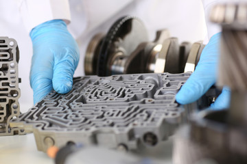 The auto repair service repairman automatic gearboxes holds in his hand in blue protective gloves...