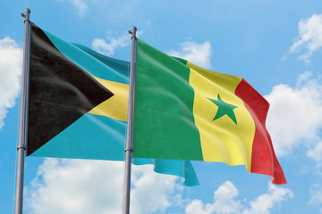 Senegal and Bahamas flags waving in the wind against white cloudy blue sky together. Diplomacy concept, international relations.