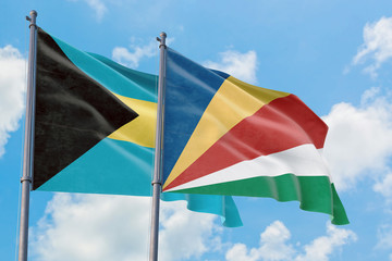Seychelles and Bahamas flags waving in the wind against white cloudy blue sky together. Diplomacy concept, international relations.