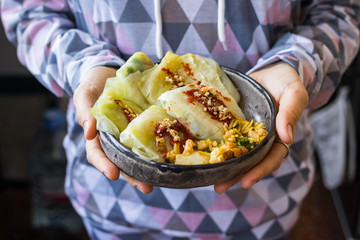 Cabbage rolls with mushrooms and tomato paste sauce walnuts topping. Healthy dietary vegan food. Woman holds cabbage rolls