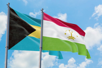 Tajikistan and Bahamas flags waving in the wind against white cloudy blue sky together. Diplomacy concept, international relations.