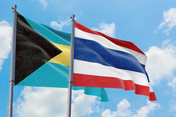 Thailand and Bahamas flags waving in the wind against white cloudy blue sky together. Diplomacy concept, international relations.
