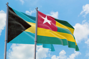 Togo and Bahamas flags waving in the wind against white cloudy blue sky together. Diplomacy concept, international relations.