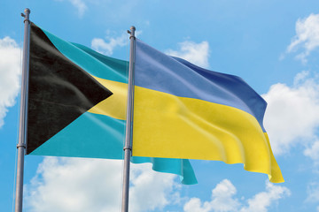 Ukraine and Bahamas flags waving in the wind against white cloudy blue sky together. Diplomacy concept, international relations.