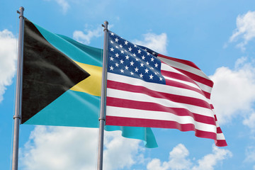 United States and Bahamas flags waving in the wind against white cloudy blue sky together. Diplomacy concept, international relations.