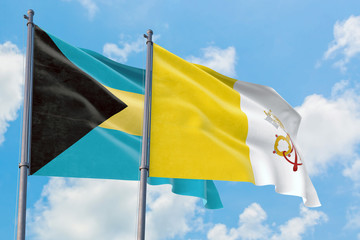 Vatican City and Bahamas flags waving in the wind against white cloudy blue sky together. Diplomacy concept, international relations.