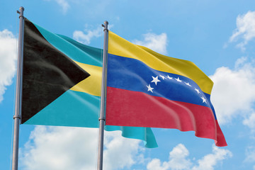 Venezuela and Bahamas flags waving in the wind against white cloudy blue sky together. Diplomacy concept, international relations.