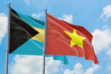 Vietnam and Bahamas flags waving in the wind against white cloudy blue sky together. Diplomacy concept, international relations.