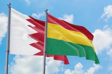 Bolivia and Bahrain flags waving in the wind against white cloudy blue sky together. Diplomacy concept, international relations.