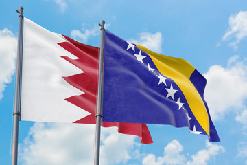 Bosnia Herzegovina and Bahrain flags waving in the wind against white cloudy blue sky together. Diplomacy concept, international relations.