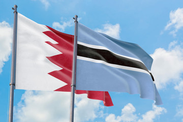 Botswana and Bahrain flags waving in the wind against white cloudy blue sky together. Diplomacy concept, international relations.