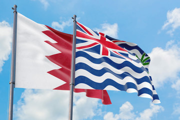 British Indian Ocean Territory and Bahrain flags waving in the wind against white cloudy blue sky together. Diplomacy concept, international relations.