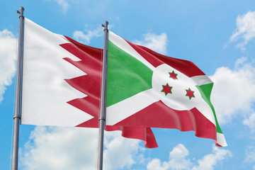 Burundi and Bahrain flags waving in the wind against white cloudy blue sky together. Diplomacy concept, international relations.