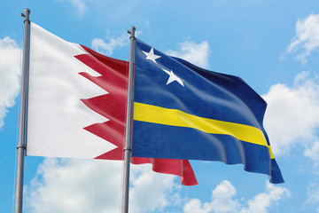 Fototapeta na wymiar Curacao and Bahrain flags waving in the wind against white cloudy blue sky together. Diplomacy concept, international relations.