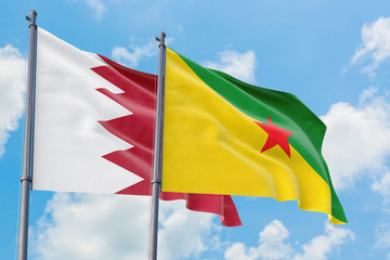 French Guiana and Bahrain flags waving in the wind against white cloudy blue sky together. Diplomacy concept, international relations.