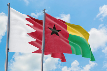 Guinea Bissau and Bahrain flags waving in the wind against white cloudy blue sky together. Diplomacy concept, international relations.