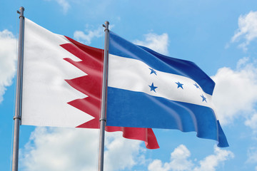 Honduras and Bahrain flags waving in the wind against white cloudy blue sky together. Diplomacy concept, international relations.