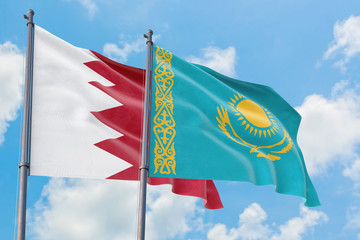 Kazakhstan and Bahrain flags waving in the wind against white cloudy blue sky together. Diplomacy concept, international relations.